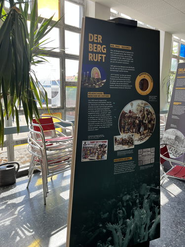 Ein Aufsteller mit Ausstellungsinhalten, Texten und Bildern steht im Foyer des Gebäudes