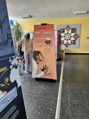 Zu sehen sind mehrere Aufsteller der Ausstellung zu verschiedenen Themen um Rassismus und Kolonialismus auch heute. Im Bild ist am deutlichsten ein Aufsteller zu Afrodeutsch zu sehen.