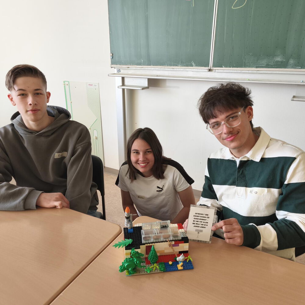 Eine Gruppe Schülerinnen und Schüler, die mit Legosteinen ihre Vision des idealen Wohnortes nachstellen